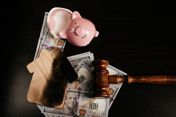Broken piggy bank, gavel and a burnt house on dollar banknotes. Lost savings