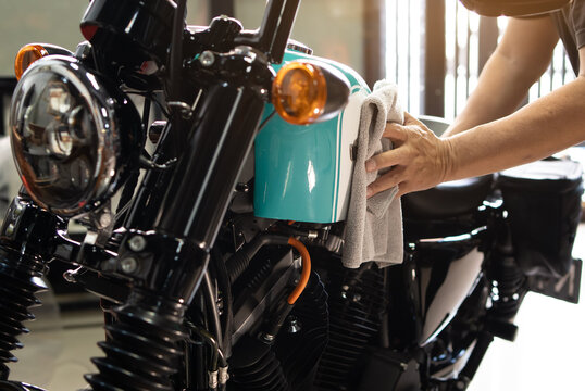 Biker Man Cleaning Motorcycle , Polished And Coating Wax On Fuel Tank At Garage. Repair And Maintenance Motorcycle Concept.