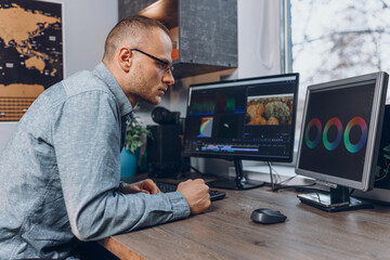 Side view of focused male movie colorist using professional software during video editing in home office 