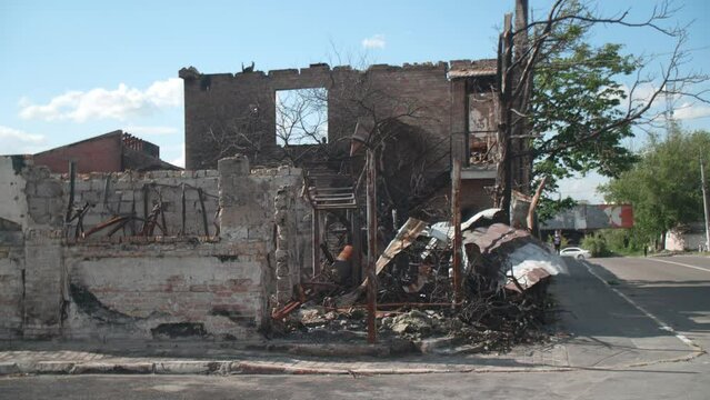 March, 2022. Irpin, Ukraine. Civil industrial block in peaceful small town destroyed by missiles. Blown-up building by the road with vehicles and a pedestrian. High quality 4k footage