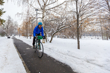 A man rides a bicycle in a winter park. Eco-friendly transport in winter. Active lifestyle