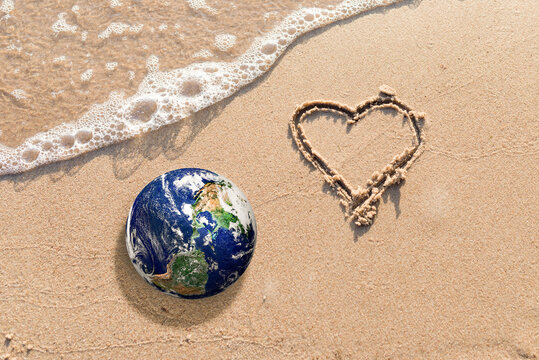World earth globe,Heart Drawn in the Sand on a Beach.Love and take care of our Natural world with our hearts concept.Elements of this image furnished by NASA.