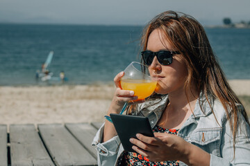 relaxed woman using digital tablet on outdoor terrace with beach background