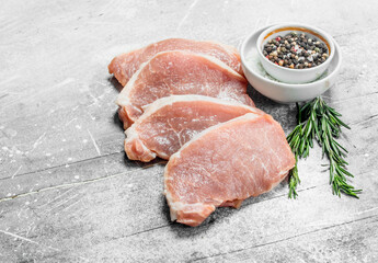 Raw pork steaks with spices and herbs.