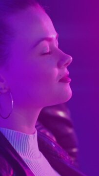 Neon light portrait. Relaxed woman. Nightclub joy. Pretty sensual lady enjoying moment in purple glow. Vertical video.