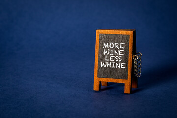 More Wine Less Whine. Miniature chalkboard on a blue background