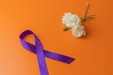 Orange background with flowers and purple bow as a symbol of the celebration of Women's Day