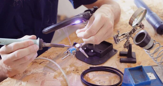 Electronics serviceman applying tin at micro switch contacts using soldering iron, close up
