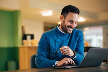 Adult businessman taking a work break, surfing the web over the laptop.