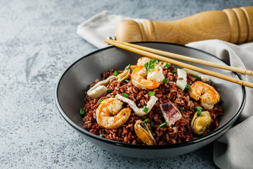 delicious red rice with shrimps and seafood on a gray stone background