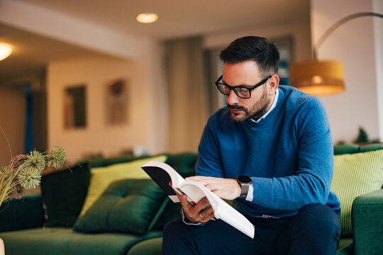 Adult male businessman reading a book at home.