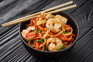 fried wok shrimp noodles on a black wooden rustic background