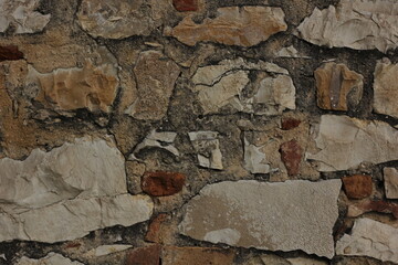 Background of an ancient brick wall, consisting of different stones and pieces of marble