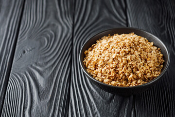 fresh raw buckwheat flakes on a black wooden background