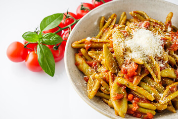 green cavatelli pasta with spinach in tomato sauce on a white background