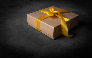 Gift box with golden ribbons on a dark mysterious background.