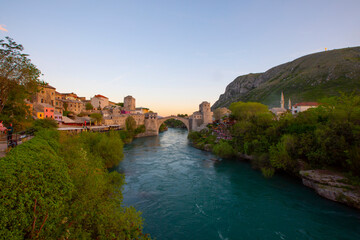 Fantastic Skyline of Mostar with the Mostar Bridge, houses and minarets, at sunset. Location:...