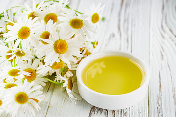 aromatic chamomile essential oil on a white wooden rustic background