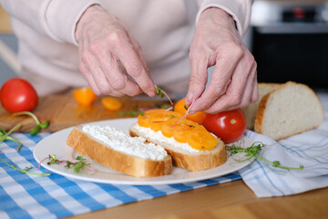 Age woman preparing healthy sandwiches with microgreens and vegetables