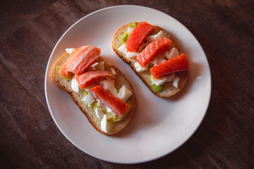 Sandwiches with avocado and red fish on a white plate