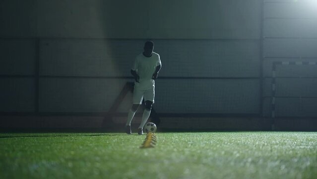 athletic black man training in football club in sport arena, full-length shot in stadium slow motion
