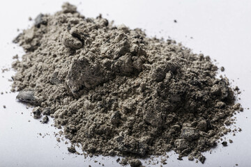 Wood ash on a white background, the grey powder contrasts with the white background, creating a...