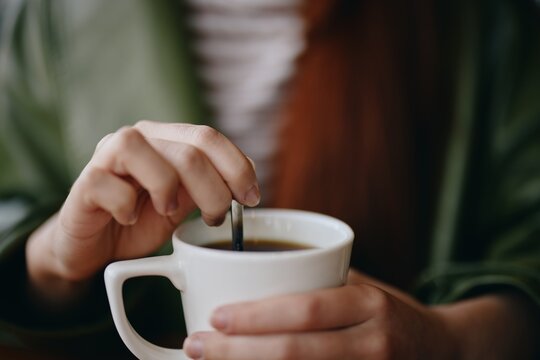 Woman in cafe stirring sugar in white coffee mug, autumn vibe and warm content for social media, blogger