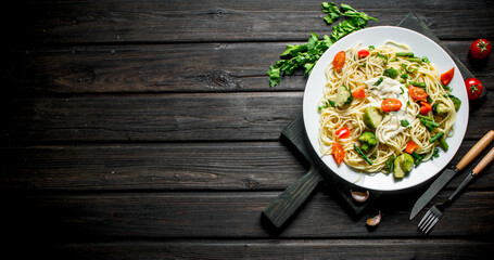 Pasta with vegetables and sauce on a plate.