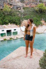Obraz premium Woman standing on a ledge over the sea in beautiful soft sunlight, Cala Pi