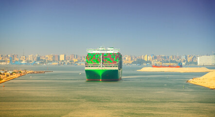 Large container ship, accompanied by tugboat, passing through the Suez Canal in Egypt.