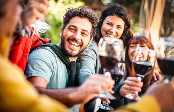 Happy people on genuine mood drinking red wine at pic nic garden party - Millenial friends having fun together at restaurant winery bar out side - Dining life style concept on bright warm filter