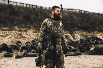 Dark-haired bearded man in military uniform looking determined