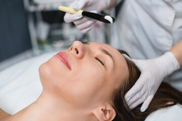Naklejka premium Cosmetologist put white mask at female face