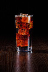 Cola with ice. Fresh cold sweet drink with ice cubes. On a black background with copy space.