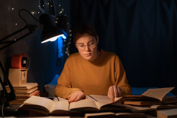 Female college student studying in dormitory reading books at late night.