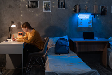Female student preparing for university exams at dormitory room at late night