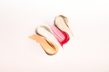 Make-up swatches, creamy in red, white, beige, and skin color on a white background.