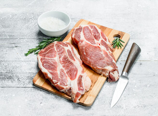 Raw pork steaks with salt.