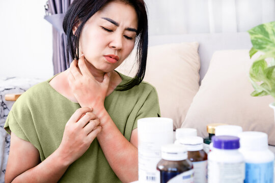 Asian Woman Have Allergic Reactions To Supplements, Multivitamins Hand Scratching On Itchy, Rash Skin That Has Side Effects With Many Bottles Of Drugs