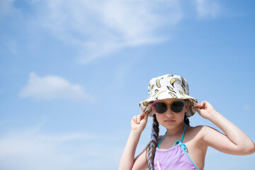 A happy girl is resting on the sea, wearing a hat, a swimsuit and sunglasses. Summer holidays, traveling with children. The concept of outdoor recreation is Good life.