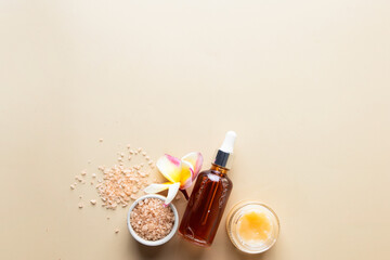 Beauty Spa salon concept.Natural oil, hydrating cream, sant scrab and frangipani flower on beige background.Flat lay
