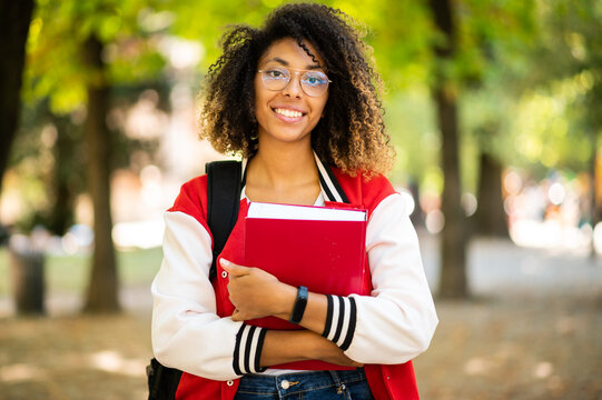 Female african student holding a book in a college park