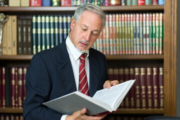 Man reading a book in his library