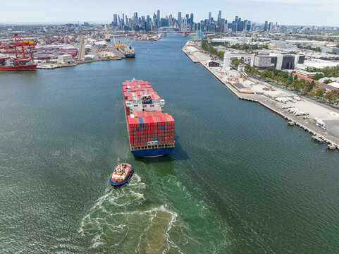 Aerial view of a tugboat moving a large cargo ship up a river