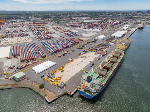 Aerial view of a cargo ship with its holds open at wharf lined with rows of containers