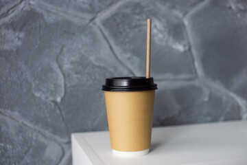 A disposable eco-friendly paper cup with a straw is on the shelf