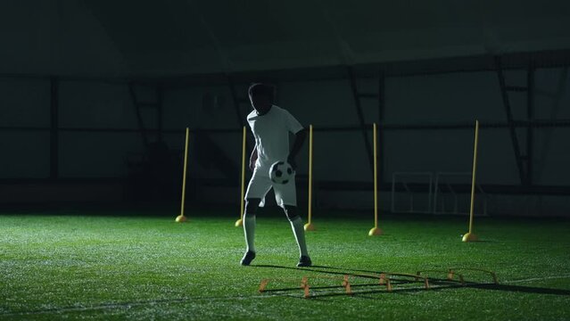 training facility of national football team, black player juggling ball in indoor sport hall
