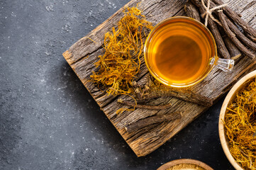 Glass cup of licorice tea with licorice root and fiber on rustic background, alternative medicine ( glycyrrhiza glabra ) - obrazy, fototapety, plakaty