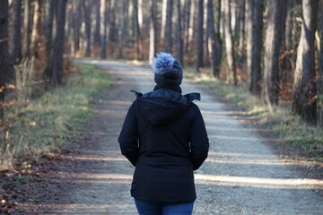 Kobieta w czapce spaceruje po lesie - obrazy, fototapety, plakaty