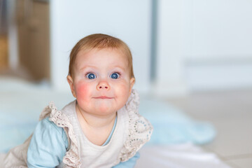 Baby girl with closed lip funny expression leaning forwards